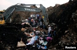 Rescue workers watch as excavators dig into a pile of garbage in search of missing people following a landslide when a mound of trash collapsed on an informal settlement at the Koshe garbage dump in Ethiopia's capital Addis Ababa, March 13, 2017.