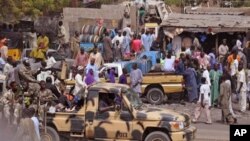 Nigerian soldiers, left, pass on the back of a armed truck as they patrol at a local market Tuesday, Jan. 27, 2015, after recent violence in surrounding areas at Maiduguri, Nigeria. Islamic extremists are rampaging through villages in northeast Nigeria’s Adamawa state, killing, burning and looting with no troops deployed to protect civilians, fleeing villagers said. Government officials say national security is one reason for delays in issuing visas to journalists. (AP Photo/Jossy Ola)