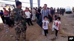 A Kurdish policeman stands guard while refugees from Mosul head to the self-ruled northern Kurdish region in Irbil, Iraq, 350 kilometers (217 miles) north of Baghdad, June 10, 2014.
