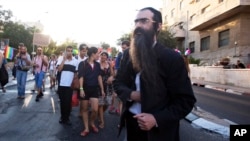Yahudi Ultra-Ortodoks Yishai Schlissel di tengah pawai Gay Pride di Yerusalem, sebelum menarik pisau dari dalam mantelnya dan menikami orang-orang (30/7). (AP/Sebastian Scheiner)