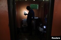 Ana Perez uses a solar lamp inside the bathroom of her home, Jan. 26, 2018, after Hurricane Maria damaged the electrical grid in Sept. 2017, in Naguabo.