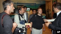 Freed journalists from Agence France Press (AFP) Roberto Schmidt (C) and Dave Clark (2nd-R) and Getty photographer Joe Raedle (L) speak to the press after their release in Tripoli, March 23, 2011