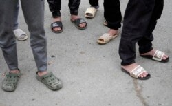 塞尔维亚北部城镇兹雷尼亚宁附近一家中国汽车轮胎工厂建筑工地工作的越南工人光着脚站在工房前。（2021年11月18日）