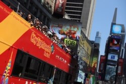 Para turis menikmati suasana di Times Square, New York sebelum pandemi dengan menaiki bus wisata "Sightseeing" (foto: dok).