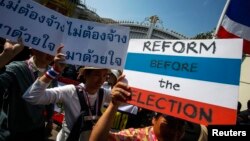 FILE - Anti-government protesters carry placards during a mass rally outside the house of Prime Minister Yingluck Shinawatra in Bangkok, Dec. 22, 2013.