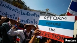 FILE - Anti-government protesters carry placards during a mass rally outside the house of Prime Minister Yingluck Shinawatra in Bangkok, Dec. 22, 2013.