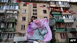 Wakazi wakikusanya vioo vya madirisha vilivyovunjika baada ya mlipuko wa ndege isiyo na rubani ya Russia iliyoanguka katika majengo ya makazi huko Kyiv Novemba 25, 2023, (Picha na Sergei SUPINSKY / AFP)