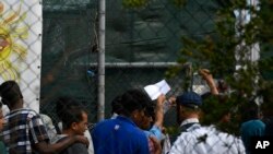 FILE - Migrants and refugees wait in a queue for the doctor at the Moria refugee camp on the northeastern Aegean island of Lesbos, Greece, Sept. 25, 2019. 
