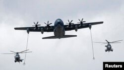 A U.S. Air Force KC130J refueling tanker and two French Caracal helicopters fly over the Champs Elysees during the Bastille Day military parade in Paris, France, July 14, 2016. 