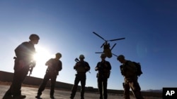 FILE - American soldiers wait on the tarmac in Logar province, Afghanistan, Nov. 30, 2017.