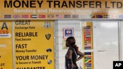 A woman looks at the closed doors of a money-transfer service in Nairobi, Kenya Wednesday, April 8, 2015. The Kenya government said Wednesday that it was freezing the accounts of a list of companies and individuals identified because of suspicious transactions, with the list including some money-transfer services dealing in remittances to Somalia. (AP Photo/Khalil Senosi)