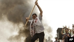 A protester jumps over burning posters of former Iraqi Prime Minister Ayad Allawi and Firas al-Jabouri, alleged al-Qaida member detained recently, during a protest at Tahrir Square in Baghdad, June 10, 2011.