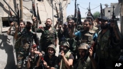 Syrian soldiers cheer after battling with rebels during a tour for journalists organized by the Syrian Information Ministry in the Damascus suburb of Jobar, Syria, July 14, 2013.