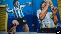 Seorang penggemar, Augusto Canosa, berdoa sambil menyentuh lukisan Diego Maradona dekat stadion Boca Juniors di Buenos Aires, Argentina, 27 November 2020. 