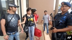 A policeman stands guard as asylum-seekers from Afghanistan, Iraq, and Iran are moved from a detention house to be transferred to Jakarta before leaving the country on May 27, 2011.