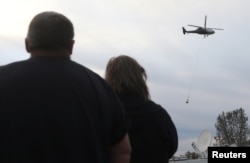 People watch as helicopters haul rock to the Lake Oroville Dam after an evacuation was ordered for communities downstream from the dam in Oroville, Calif., Feb. 13, 2017.
