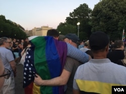 Many partners at the vigil hugged, wrapping the rainbow flags of gay pride around each other. (K. Gypson/VOA)