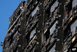 FILE - A worker looks from top of the building as nearly a third of the Grenfell Tower apartment building is covered with scaffolding in London, Feb. 1, 2018