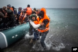 FILE - Refugees and migrants disembark on a beach after crossing a part of the Aegean sea from Turkey to the Greek island of Lesbos.