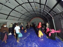 Pengungsi Rohingya memasuki tenda darurat yang dipasang oleh pihak berwenang di Kabupaten Aceh Timur, Jumat, 4 Juni 2021. (Foto: VOA/Anugrah)