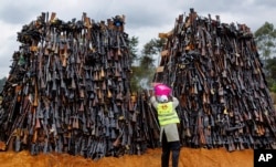 A man pours fuel on a pile of 5,250 illegal weapons before they were burned by Kenyan police in Ngong, near Nairobi, in Kenya, Nov. 15, 2016.