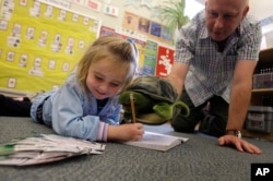 Teacher Matt Bugaj uses a Twiggle the Turtle hand puppet to teach a "Twiggle the Turtle" conflict resolution lesson to Kaylee Schaefer, 4, at Bennett Family Child Care Center in University Park, Pa., Friday, Nov. 14, 2008. (AP Photo/Carolyn Kaster)