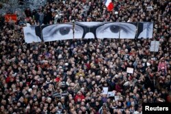 FILE - Marchers carry panels showing the eyes of Charlie Hebdo’s slain editor, Stephane Charbonnier, in the streets of Paris, Jan. 11, 2015.