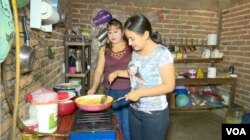 Under the supervision of her mother-in-law, left, Estrella, married at 13, learns to cook. She wakes up early to have her husband’s coffee ready by 5:40 a.m. or 6 a.m. (Photo by Ery Acuna Meneses for VOA News)