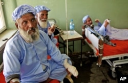 Afghan men, among nearly a dozen people who had their fingers cut off by Taliban fighters as a punishment for voting in this weekend's presidential runoff, rest in a hospital in Herat, Afghanistan, June 15, 2014.