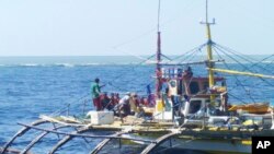 FILE - In this photo provided by Renato Etac, Chinese Coast Guard members, wearing black caps and orange life vests, approach Filipino fishermen as they confront them off Scarborough Shoal at South China Sea in northwestern Philippines, Sept. 23, 2015.