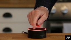 In this March 2, 2016, file photo, David Limp, Amazon Senior Vice President of Devices, pushes down on an Echo Dot in San Francisco. (AP Photo/Jeff Chiu, File)