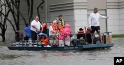 Residents are evacuated from their homes surrounded by floodwaters from Tropical Storm Harvey Sunday, Aug. 27, 2017, in Houston, Texas.