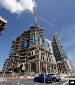 FILE - A high-rise building under construction is shown next to a high-rise condominium building, Sept. 7, 2017, in downtown Miami.