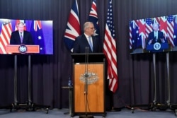 Australia's Prime Minister Scott Morrison, center, appears on stage with video links to Britain's Prime Minister Boris Johnson, left, and U.S. President Joe Biden at a joint press conference at Parliament House in Canberra, Thursday, Sept. 16, 2021.