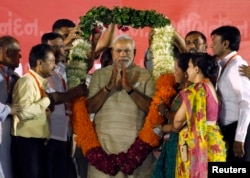 FILE - Hindu nationalist Narendra Modi, who will be the next prime minister of India, wears a garland presented to him by his supporters at a public meeting in the western Indian city of Ahmedabad, May 20, 2014