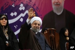 Iranian President Hassan Rouhani, center, waves to his supporters as he is accompanied by Vice President for Women and Family Affairs Shahindokht Molaverdi in a campaign rally for the May 19 presidential election in Tehran, Iran, May 9, 2017.