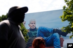 People walk past a billboard for the CNN television show "Parts Unknown" with American celebrity chef Anthony Bourdain, Friday, June 8, 2018 in Atlanta, Georgia.