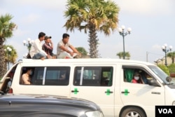 អ្នកធ្វើដំណើរ​ ៣រូប​ អង្គុយ​លើ​ដំបូល​នៃ​រថយន្តឈ្នួល​ ទៅកាន់​ស្រុក​កំណើត នា​ឱកាស​បុណ្យ​ចូលឆ្នាំ​ខ្មែរ​ ក្នុង​រាជធានី​ភ្នំពេញ​ នៅ​ថ្ងៃទី​១៣ ខែ​មេសា​ ឆ្នាំ​២០១៧។ (ហ៊ាន សុជាតា/ VOA)