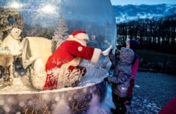 A person dressed as a Santa Claus meets with children while sitting in a "Santa Claus bubble" as he opens Christmas season at Aalborg Zoo, amid the coronavirus outbreak, in Aalborg, Denmark.