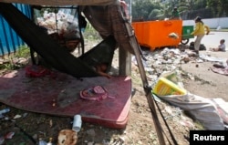 A young girl sleeps in a hammock as her mother clears garbage, along a street in central Phnom Penh October 3, 2014. REUTERS/Samrang Pring