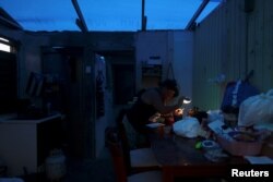 A woman uses a flashlight while trying to connect a transformer to a car battery in Maunabo, Puerto Rico, Jan. 27, 2018.