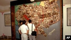 Visitors to Toul Sleng, officially known as S-21 prison look at a wall of sculls and bones made into a map of Cambodia.