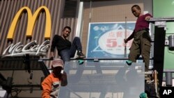 FILE - Workers install glass panels near a McDonald's in Beijing, Nov. 7, 2017. "Some companies will inevitably suffer some repercussions if there are trade frictions between the two countries," says Lester Ross, head of AmCham China’s policy committee.