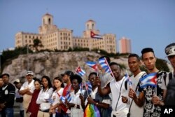 Backdropped by the Hotel Nacional, people hold Cuban flags as they wait for the motorcade transporting the remains of Cuban leader Fidel Castro in Havana, Cuba, Nov. 30, 2016.