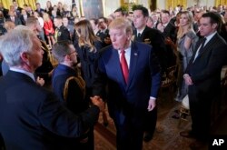 President Donald Trump stops to greet Sen. Ron Johnson, R-Wis., left, after speaking on combating drug demand and the opioid crisis in the East Room of the White House in Washington, Oct. 26, 2017.