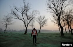 Artist Liu Bolin wearing a vest with 24 mobile phones walks in smog as he live broadcasts air pollution in the city on the fourth day after a red alert was issued for heavy air pollution in Beijing, China, Dec. 19, 2016.