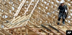 FILE - A construction worker pulls his safety rope while working on the roof of an apartment complex being built in Spring, Texas, March 27, 2015.