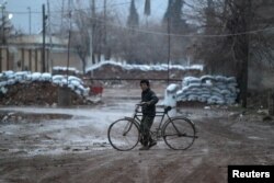 FILE - A boy walks his bike near stacked sandbags in al-Rai town, northern Aleppo province, Syria, Dec. 27, 2016.