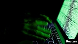 FILE - A man types on a computer keyboard in front of the displayed cyber code in this illustration picture taken on March 1, 2017.
