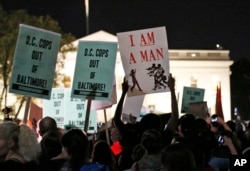 Demonstrators hold signs during a protest to support the rallies in Baltimore, in front of the White House in Washington, April 29, 2015.